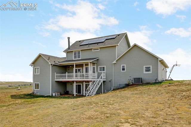 rear view of house with a yard and solar panels