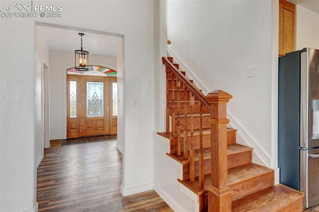 entrance foyer with dark hardwood / wood-style flooring and a notable chandelier