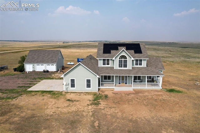 rear view of property featuring roof mounted solar panels, covered porch, a garage, an outbuilding, and roof with shingles