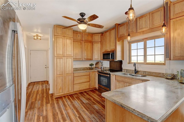 kitchen with light wood-type flooring, a peninsula, light countertops, stainless steel appliances, and a sink