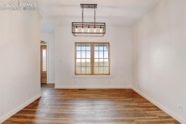 unfurnished dining area with baseboards and wood finished floors