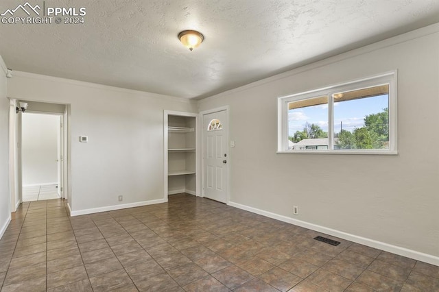 empty room featuring a textured ceiling and dark tile patterned floors