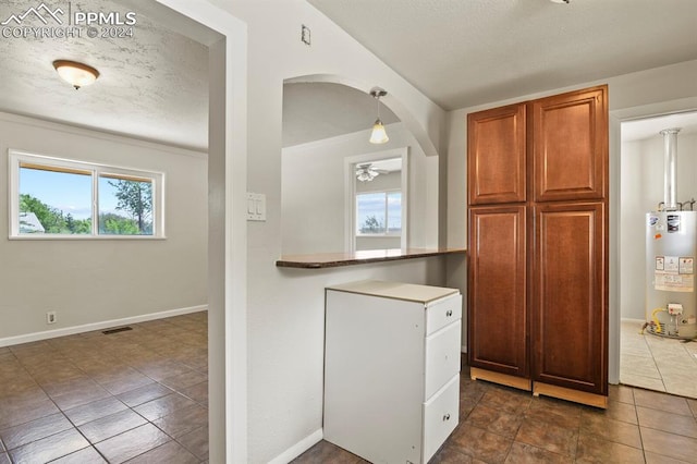 kitchen featuring water heater, dark tile patterned floors, a textured ceiling, ceiling fan, and pendant lighting