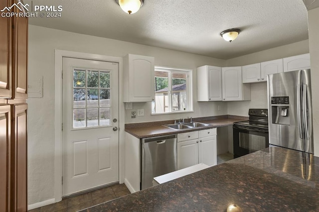 kitchen featuring stainless steel appliances, dark tile patterned floors, sink, a textured ceiling, and white cabinets