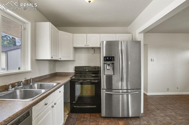 kitchen featuring appliances with stainless steel finishes, sink, white cabinets, and dark tile patterned floors