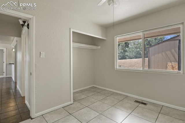 unfurnished bedroom featuring light tile patterned floors, ceiling fan, and a closet