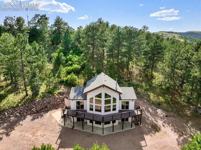 rear view of house with a wooded view and a deck