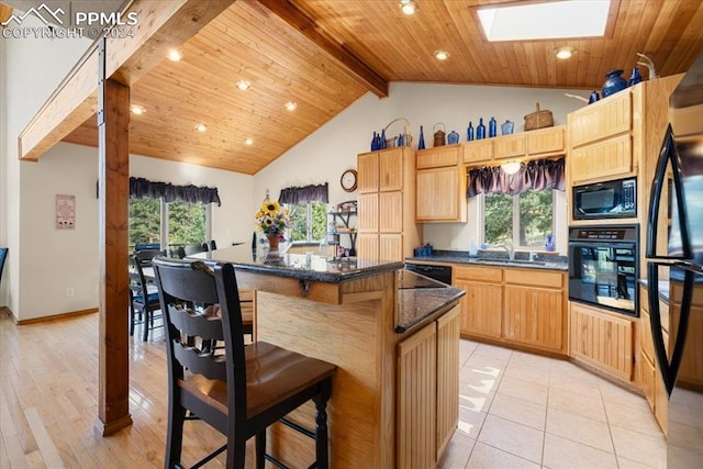 kitchen with a skylight, a center island, beamed ceiling, black appliances, and sink