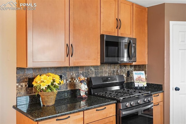 kitchen with tasteful backsplash, stainless steel range with gas stovetop, and dark stone counters