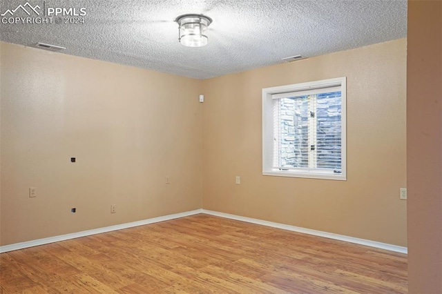 empty room featuring a textured ceiling and light wood-type flooring