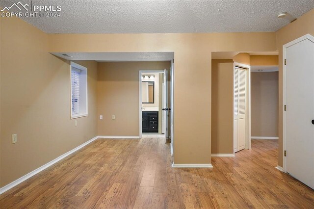 unfurnished room featuring light hardwood / wood-style floors and a textured ceiling