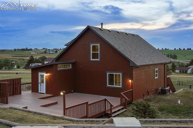 rear view of property with cooling unit, a deck, and a rural view