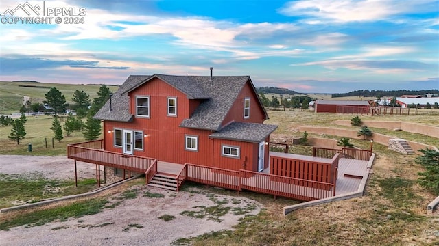 back house at dusk featuring a deck