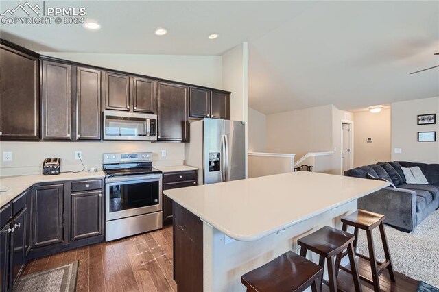 kitchen featuring a kitchen island, vaulted ceiling, dark hardwood / wood-style floors, dark brown cabinets, and appliances with stainless steel finishes