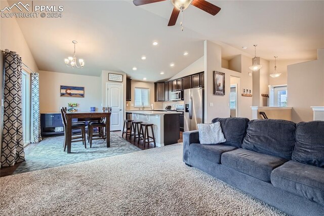 living room featuring ceiling fan with notable chandelier, plenty of natural light, and dark colored carpet