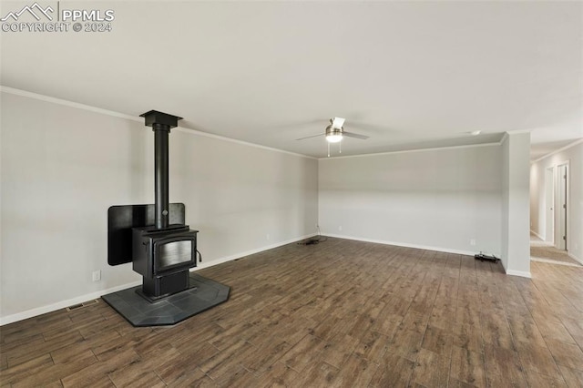 unfurnished living room with ceiling fan, crown molding, wood-type flooring, and a wood stove