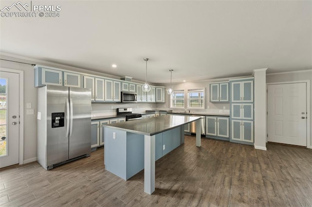 kitchen featuring dark hardwood / wood-style floors, hanging light fixtures, a breakfast bar, appliances with stainless steel finishes, and a center island