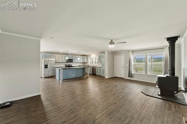 unfurnished living room featuring ceiling fan, dark hardwood / wood-style floors, crown molding, and a wood stove