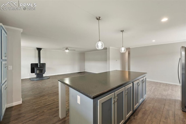 kitchen featuring a kitchen island, dark wood-type flooring, a wood stove, and hanging light fixtures