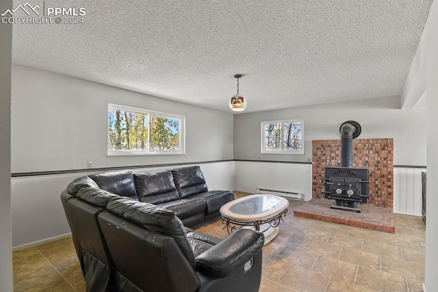 living room with plenty of natural light, a wood stove, a baseboard radiator, and a textured ceiling