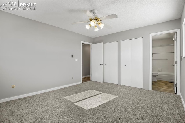 unfurnished bedroom with ceiling fan, a textured ceiling, carpet flooring, multiple closets, and connected bathroom