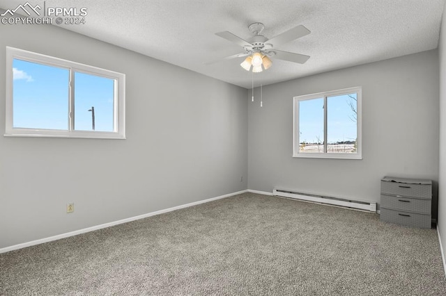 carpeted empty room with ceiling fan, a baseboard radiator, plenty of natural light, and a textured ceiling