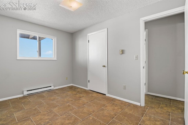 unfurnished room with a textured ceiling and a baseboard heating unit