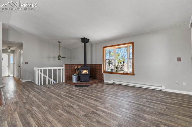 unfurnished living room featuring wood-type flooring, vaulted ceiling, a wood stove, and a baseboard radiator