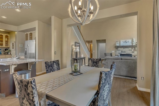 dining space featuring a chandelier, light hardwood / wood-style floors, and a stone fireplace