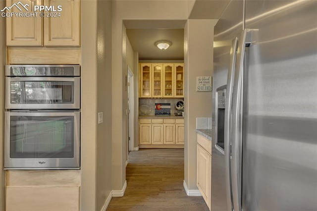 kitchen with appliances with stainless steel finishes, backsplash, and hardwood / wood-style flooring