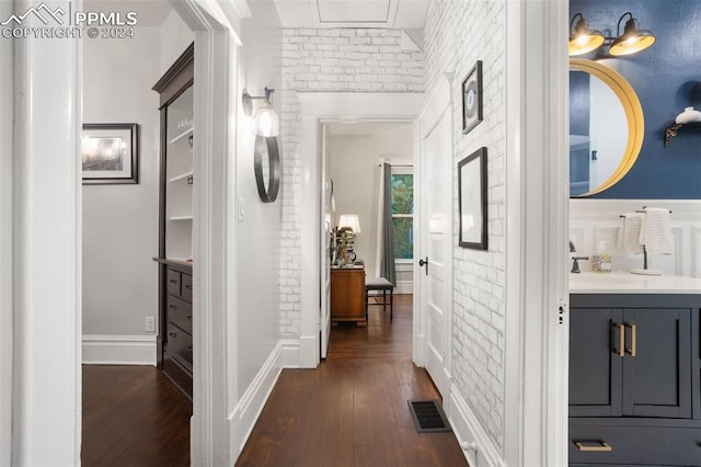 hallway with brick wall, sink, and dark hardwood / wood-style flooring