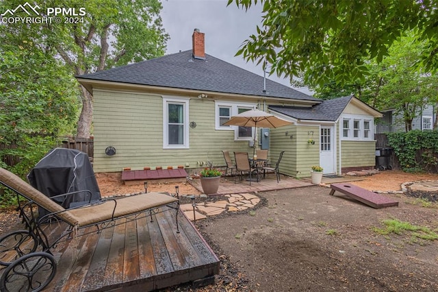 rear view of property featuring an outdoor structure, a patio area, and a wooden deck