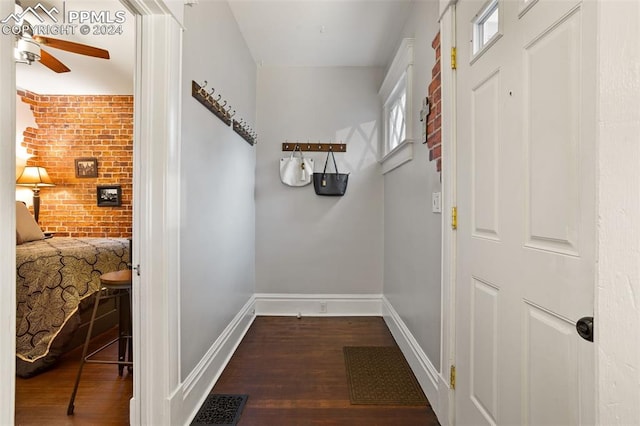 corridor featuring brick wall and dark wood-type flooring