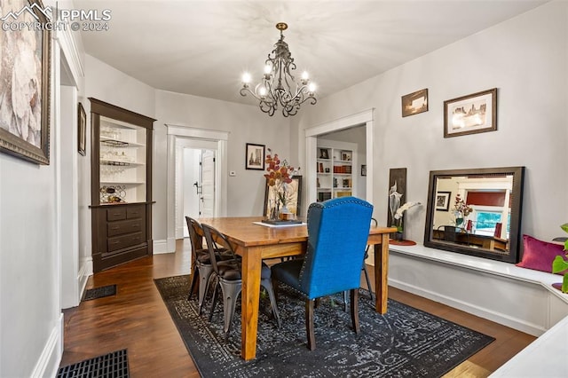 dining room with dark wood-type flooring, built in features, and a chandelier