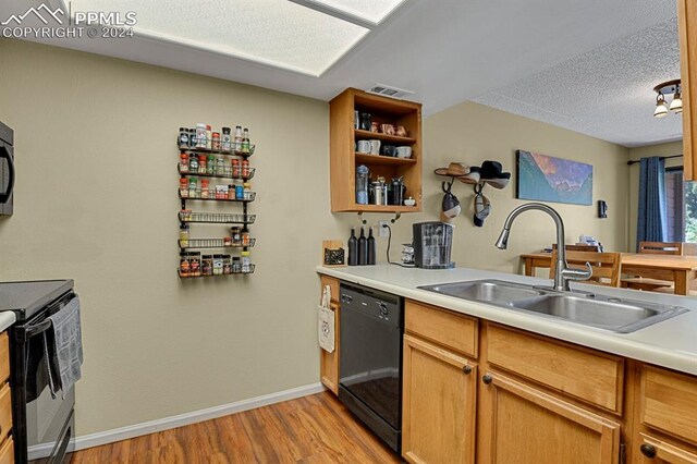 kitchen featuring light wood-type flooring, sink, black dishwasher, range with electric stovetop, and a textured ceiling