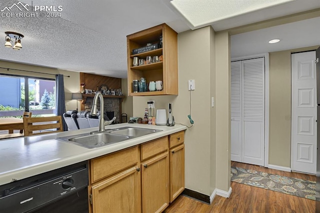 kitchen featuring dishwasher, sink, a textured ceiling, and light wood-type flooring