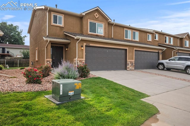 townhome / multi-family property featuring a garage and a front lawn