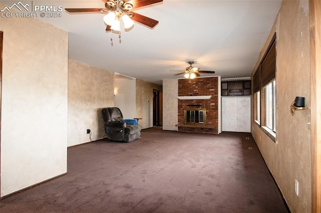 unfurnished living room featuring ceiling fan, brick wall, dark carpet, and a brick fireplace