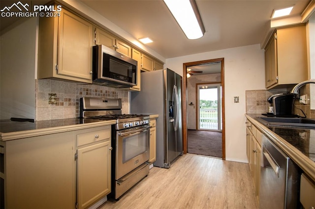 kitchen with appliances with stainless steel finishes, tasteful backsplash, sink, and light hardwood / wood-style floors