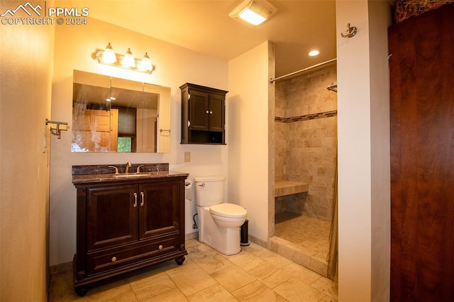 bathroom with tiled shower, toilet, tile patterned floors, and vanity