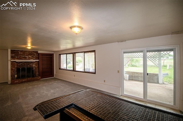 unfurnished living room with a fireplace, carpet, and brick wall