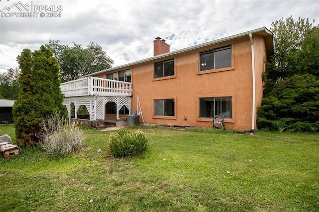 rear view of house with a lawn, central AC unit, and a deck