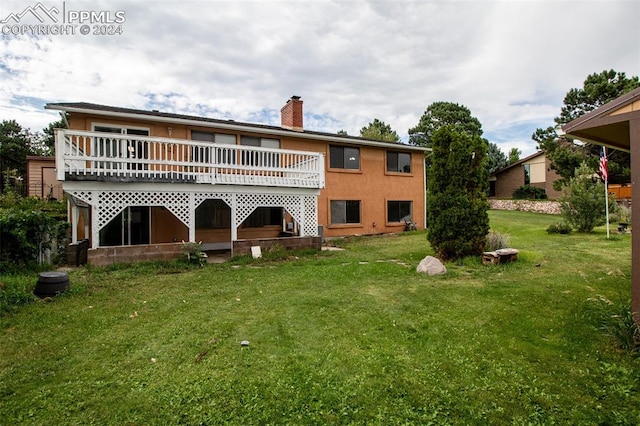 rear view of property with a wooden deck and a lawn