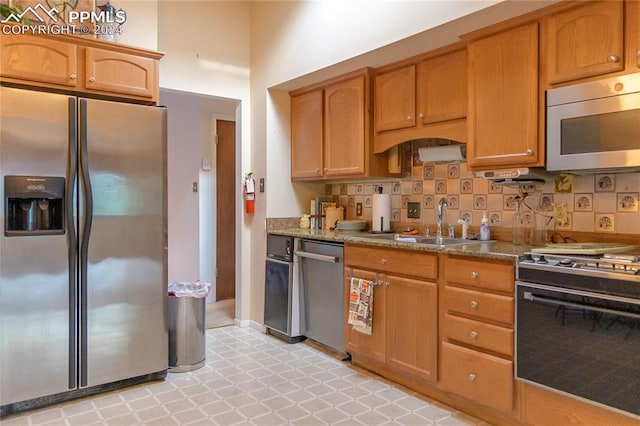 kitchen with sink, decorative backsplash, appliances with stainless steel finishes, and stone countertops