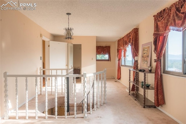 hallway with light colored carpet and a textured ceiling