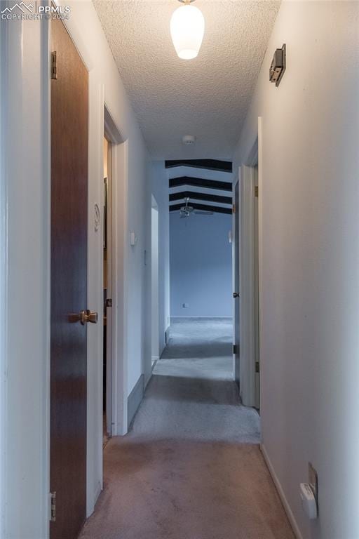 hall with light colored carpet and a textured ceiling