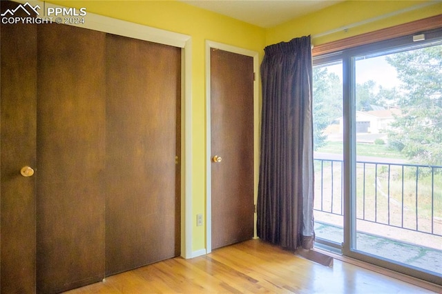 unfurnished bedroom with a closet, access to outside, and light wood-type flooring