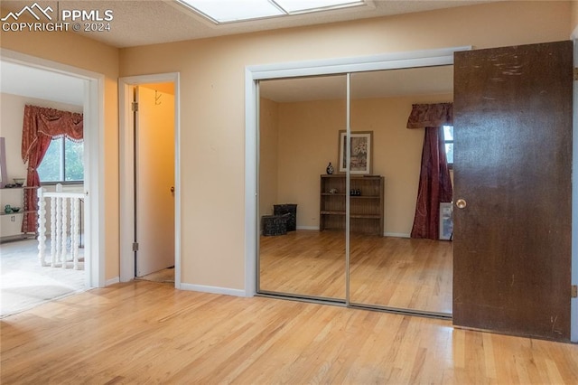 unfurnished bedroom with a skylight, wood-type flooring, and a closet