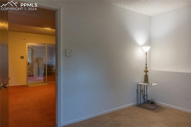 hall featuring carpet floors and a textured ceiling