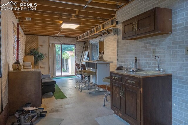 interior space featuring dark brown cabinetry, brick wall, and sink